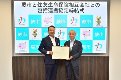 写真：協定書を持つ頼高英雄蕨市長と阿川支社長